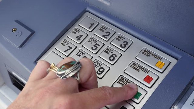 Female hand entering PIN on Greek banking machine.