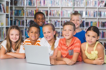 Portrait of school kids using laptop in library
