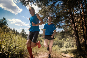 Trail running athletes crossing off road terrain at sunny day