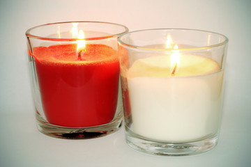 Velas blanca y roja con llama encendida sobre fondo blanco