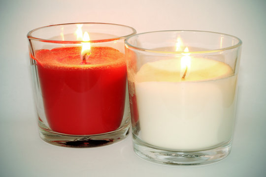 Velas blanca y roja con llama encendida sobre fondo blanco