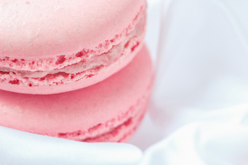 tasty pink strawberry macaroons on white silk background