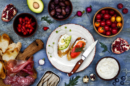 Brushetta or authentic traditional spanish tapas set for lunch table. Sharing antipasti on party or picnic time over blue rustic background. Top view.