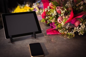 Flower bouquet with smartphone and digital tablet on the table