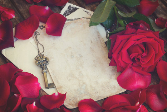 vintage background with red rose petals and antique gold key, retro toned