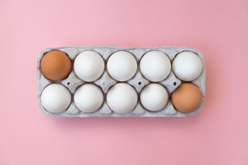 White and brown eggs in carton. Two brown eggs places on opposite.