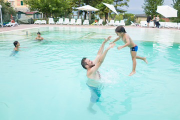 Young boy kid child splashing in swimming pool having fun leisur