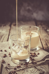Pouring coffee liqueur in glasses with ice and beans