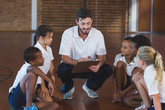Sports teacher having discussion with his students