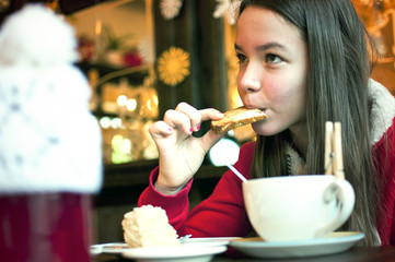 Girl with a cup of tea in a cafe eating Christmas cookies