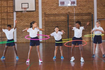 School kids playing with hula hoop in in basketball court