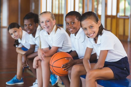 Portrait Of School Kids Sitting In Basketball Court