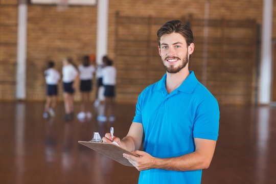 Portrait of sports teacher writing on clipboard