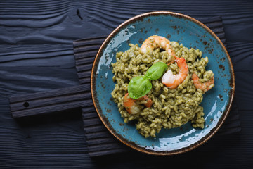 Spinach and tiger shrimps risotto on a black wooden background