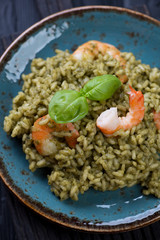 Spinach and tiger shrimps risotto topped with fresh basil leaves