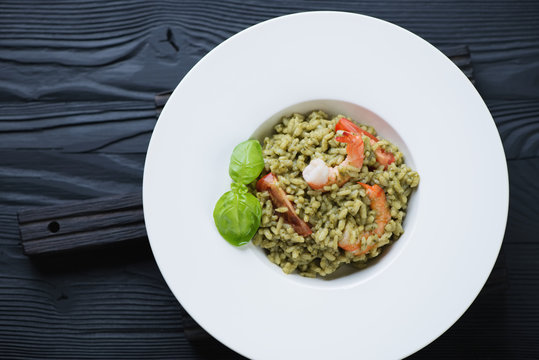White plate with spinach risotto over black wooden background