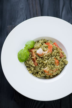 Spinach and tiger shrimps risotto in a white plate, top view
