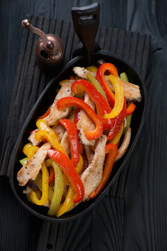Cast-iron frying pan with fajitas on a black wooden background