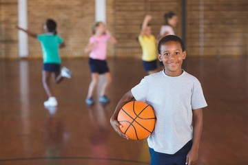 Boy standing with ball in basketball court