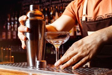bartender is making cocktail holding shaker at bar background