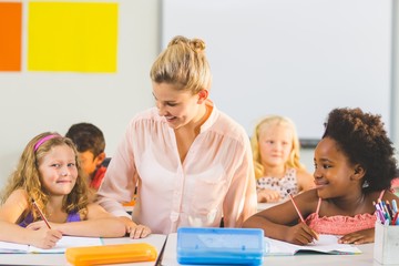 Teacher helping kids with their homework in classroom