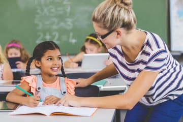 Teacher helping kids with their homework in classroom