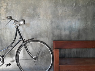 Black Bike,Bicycle vintage style on Concrete wall and wood chair.