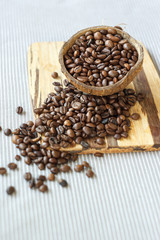 roasted coffee beans in coconut shell on rustic wooden background, Still life photography with roasted coffee beans