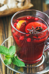 Hot red mulled wine on wooden background decorated blue spruce branches, with christmas spices, orange slice, fresh mint, cloves, anise and cinnamon sticks, close up.