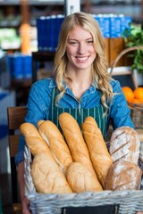 Smiling woman holding a basket of baguettes