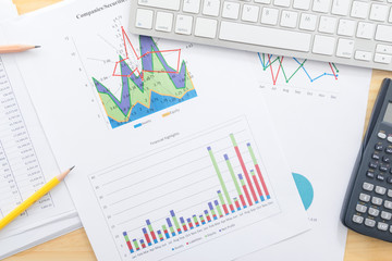 Documents report data graphs with calculator on office desk