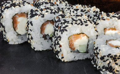 Japanese sushi roll philadelphia on black stone. Selective focus. Blurred foreground and background. Macro view