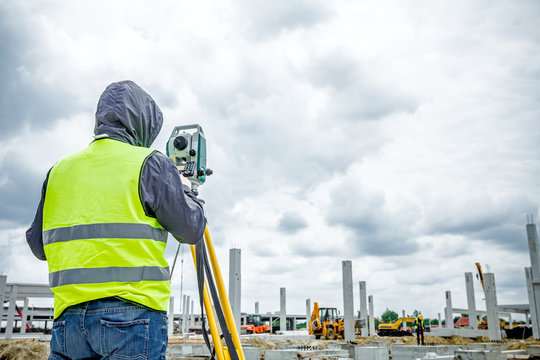 Geodesist is working with total station on a building site. Civi