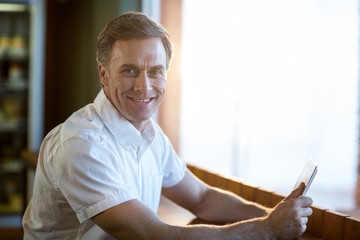 Smiling man using a digital tablet in café