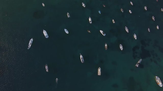 Aerial top down of boats and dinghies lying like toys in the harbour.