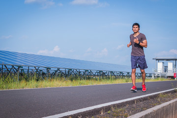 Obraz premium handsome man running on road with solar power plant in morning ;Healthy lifestyle with green energy