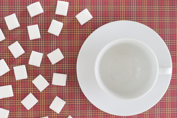 White sugar cubes and empty coffee cup on red background. Copy space. Top view