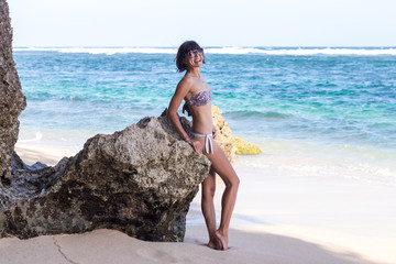 Pretty woman posing on the beach near the ocean of tropical island Bali, Indonesia.