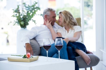 Romantic couple sitting on armchair with wine and gift box