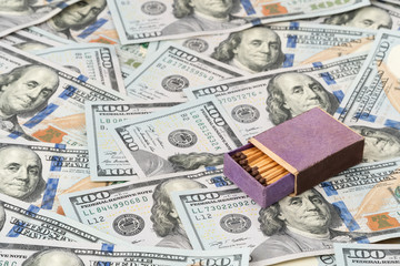 Wooden open box of matches lying on a pile of money