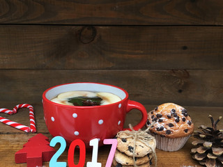 New year red cup with white dots. Christmas sweets. Wooden date 2017