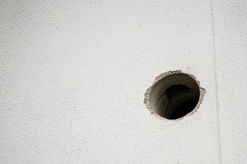 hole in white concrete wall