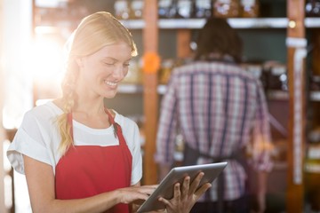 Female staff using digital tablet in supermarket