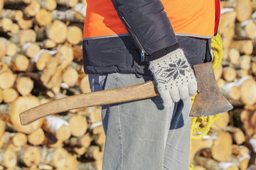 Lumberjack with ax and rope near pile of logs