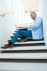 Focused man using laptop on steps