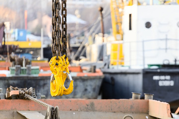 Yellow cargo hooks hanging on a steel chain.
