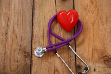 Heart with a stethoscope, isolated on wooden background