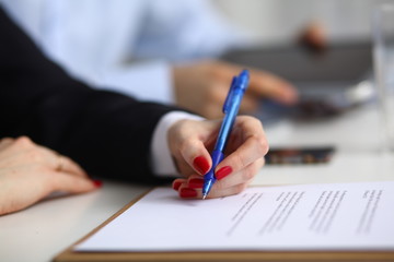Businesswoman sitting in office, writing on documents