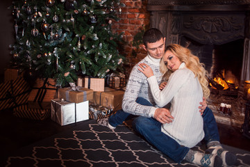 Obraz premium Merry Christmas. Young couple celebrating New Year at home. Man and woman hugging