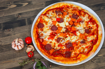 fast food. mexican pizza with pepperoni, vegetables, cheese on wood table with copy space. top view